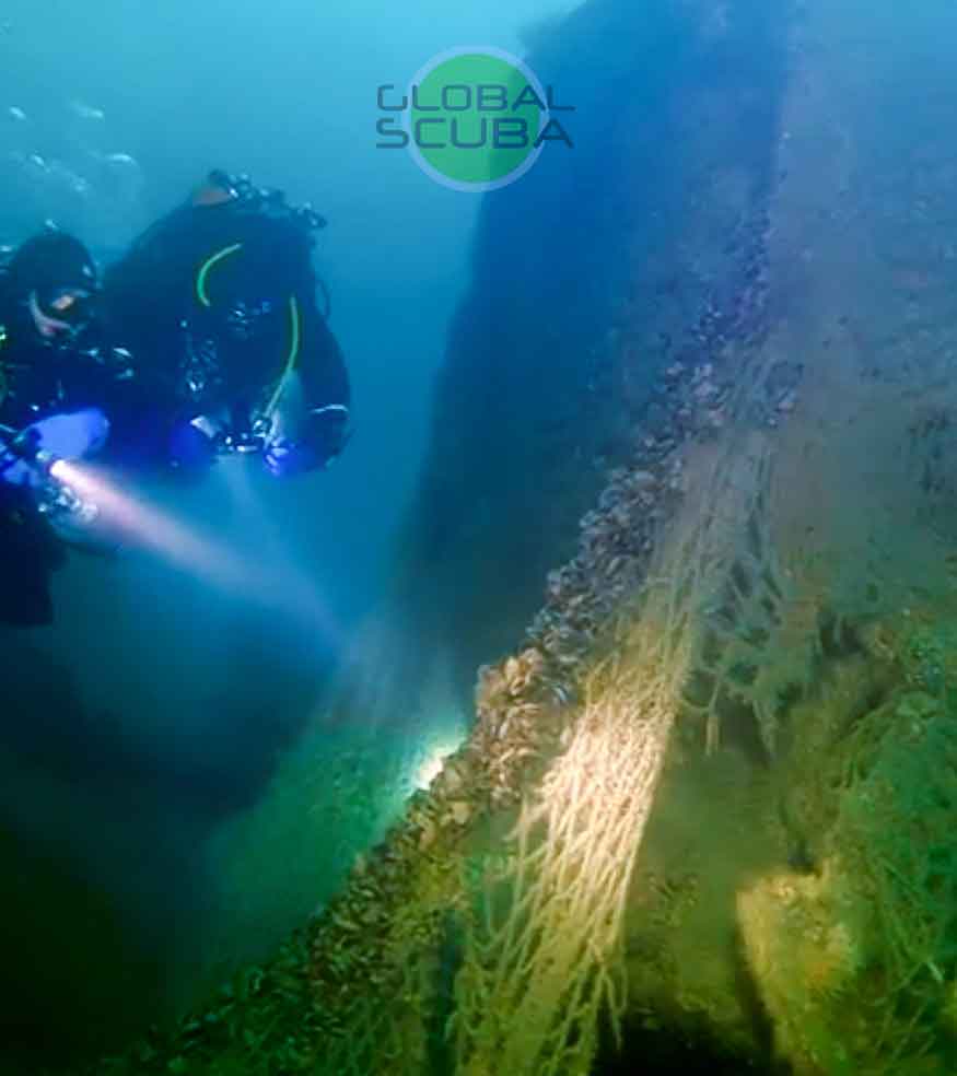 дайверы и рыбацкая сеть на дне моря в свете фонарей на фоне затонувшего корабля в геленджике